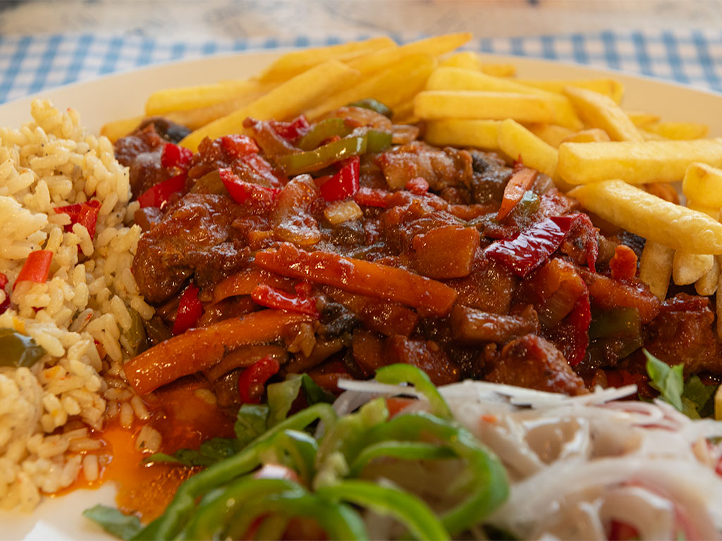 Cooked meal made from diced meat, carrots green and red peppers, served with mixed salad, rice and fries.
