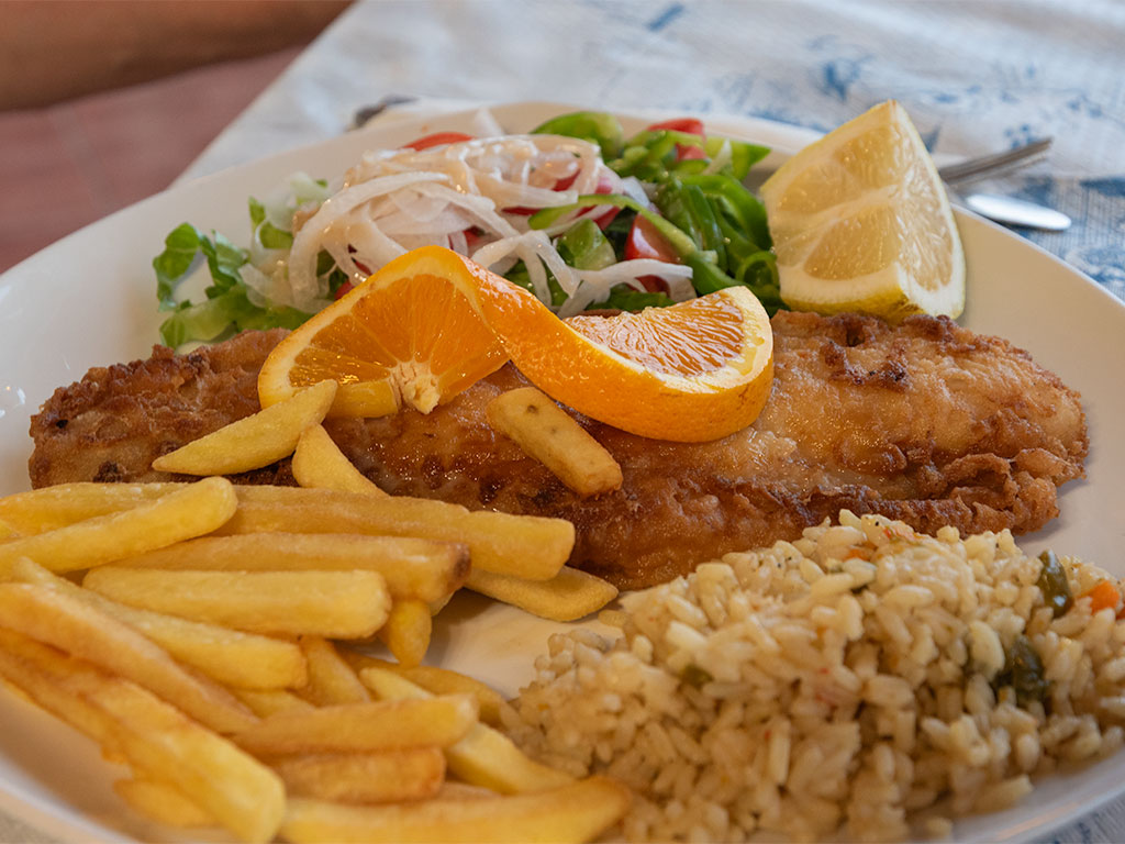Fried golden battered fish and chips served with twist of orange, slice of lemon, rice and a mixed salad.